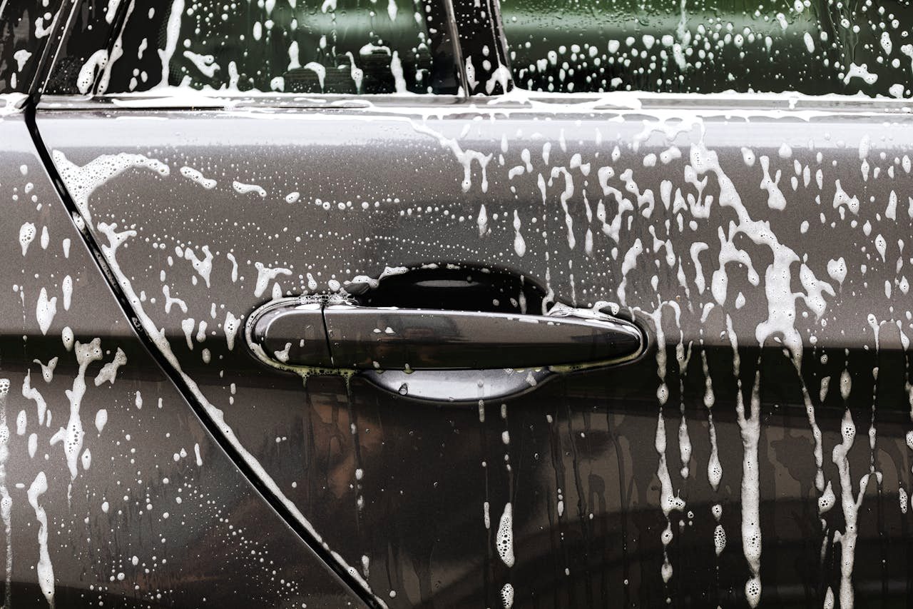 Schuim op de deurgreep van een auto tijdens de exterieurreiniging bij S.T. Detailing in Franeker